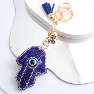 Vue détaillée du porte-clés Hamsa Hand Evil Eye bleu scintillant avec pompon bleu