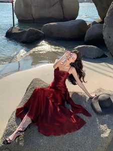 Model posing in a shimmering red mermaid dress with ruffled details on a beach