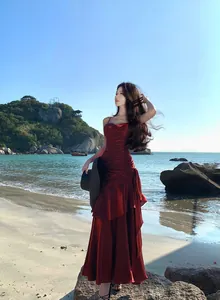 Full view of a red ruffled mermaid evening gown worn by a model on a tropical beach