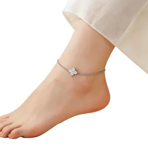 Silver-plated four-leaf clover anklet with crystal accents on a model's foot