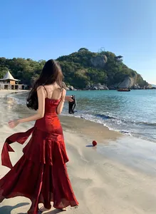 Elegant shimmering red mermaid ruffle dress for women shown on a beautiful sunny beach