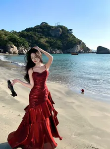 Detailed view of shimmery red mermaid ruffled banquet evening gown on a sunny beach