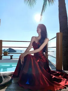 Elegant red mermaid-style dress with ruffles shown in a scenic outdoor beach setting
