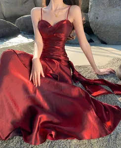Detailed view of shimmering wine red satin evening dress with elegant ruffled design and straps