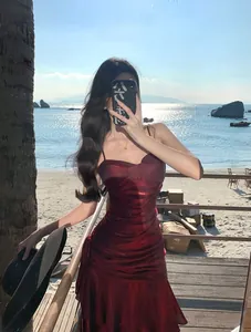 Detail of mermaid red ruffle camisole evening dress with shimmering finish by the beach