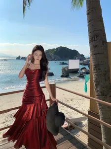 Full-length view of an elegant wine red mermaid ruffle dress at a sunny beach resort terrace