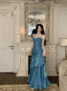 Full view of elegant blue mermaid ruffled evening gown in vintage indoor setting