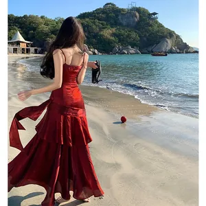 Elegant red shimmering mermaid dress with tiered ruffles on a scenic beach