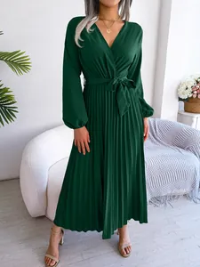 Detailed view of an elegant forest green long-sleeved pleated maxi dress on model