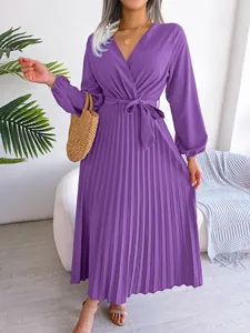 Close-up of a purple long-sleeved pleated maxi dress with a cross V-neckline and tie-waist.