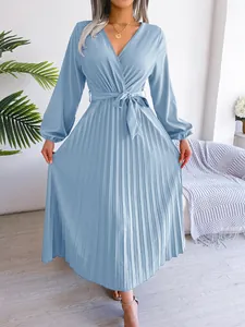 Detail view of a light blue pleated long dress with cross V-neck and belted waist