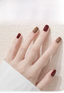 Detail view of khaki and cherry wine red water-based peelable nail polish on fingers.