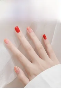 Close-up detail of manicured nails in vibrant red and glittery nude pink shades on a hand.
