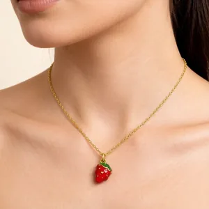 Close-up shot of a sweet red enamel strawberry pendant necklace worn by a female model