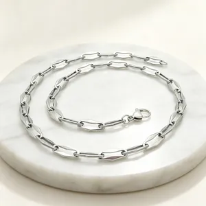 Close-up of silver stainless steel necklace with geometric hexagonal links on marble.