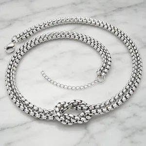 Close-up of a chunky silver stainless steel knotted chain necklace on marble background