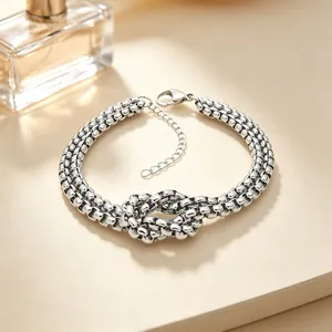 Macro view of a double-layered stainless steel bracelet featuring a central knot design
