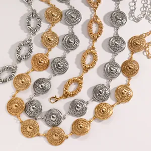 Close-up of ethnic style metal waist chains with intricate carved medallions in gold and silver.
