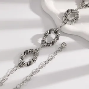 Close-up detail of a minimalist silver waist chain belt featuring twisted oval metal links