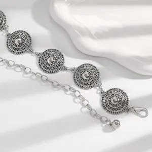 Detailed view of silver ethnic metal waist chain with intricate engraved medallion patterns