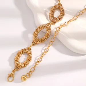 Close-up detail of a textured golden metal waist chain with elegant oval ring links