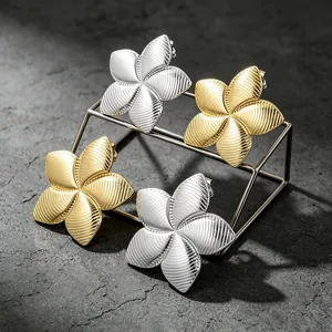 Detailed view of textured gold and silver metal flower petal earrings on a display stand