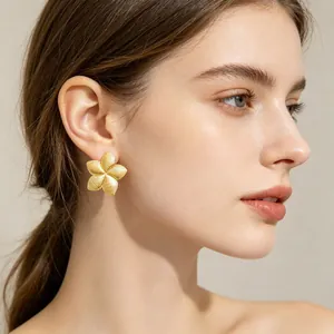 Elegant gold flower earrings with pleated texture shown on a model's ear