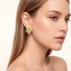 Close-up of gold-plated textured flower earrings on model showing pleated detail.