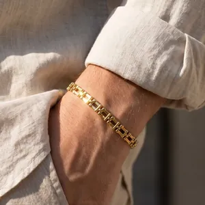 Détail macro d'un bracelet à maillons en acier inoxydable doré au poignet au soleil.