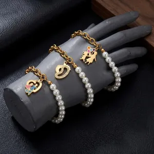 Close-up of gold titanium steel bracelets with white pearl beads and family heart pendants.