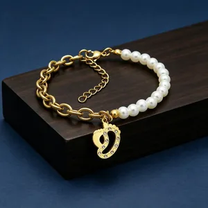 Detail of gold titanium steel bracelet with pearls and crystal foot charm