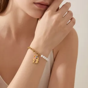 Detail of pearl and gold chain bracelet with colorful kids holding balloons charm.