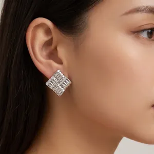 Eleganti orecchini a bottone quadrati in argento con trama a righe in rilievo su modella