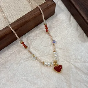 Macro view of an elegant beaded necklace featuring a vibrant red heart pendant and pearls.