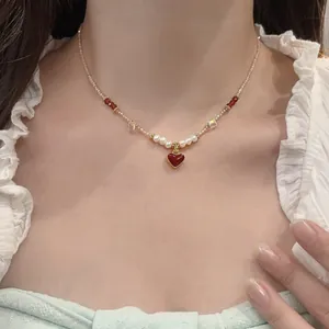 Close-up detail of an elegant beaded necklace featuring a red heart pendant and pearls.