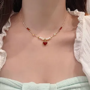 Close-up of elegant beaded necklace featuring a red heart pendant and white pearls