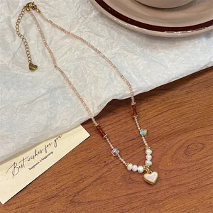 Elegant beaded necklace detail featuring white heart pendant, pearls, and crystals on paper