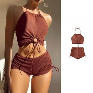 Detail view of rust two-piece swimsuit with halter top and high-waist shorts.