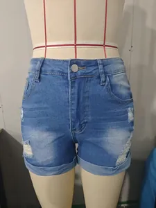 Détail du short en jean bleu à taille haute avec des déchirures et des ourlets retroussés