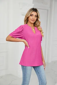 Woman wearing a bright pink V-neck eyelet top with puff sleeves and loose fit style