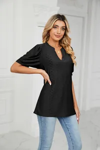 Detail view of a black V-neck top with puff sleeves and intricate hollow-out texture.