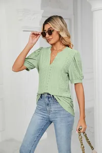 Detail of light green V-neck top with eyelet pattern and elegant puff sleeves.