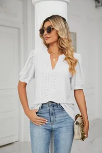 Detailed view of a white V-neck eyelet puff sleeve summer top worn by a model in a studio