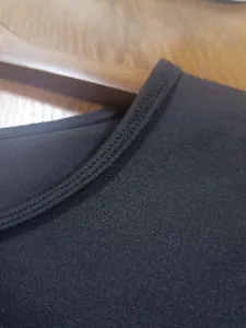 Close-up view of the double-stitched collar detail on a black casual crew neck tee