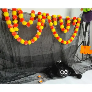 Detailed scene of orange and yellow marigold garlands with a plush spider on black mesh