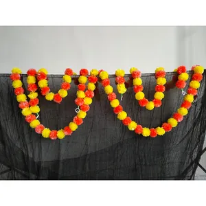 Vibrant yellow and orange artificial marigold flower garlands on black backdrop.