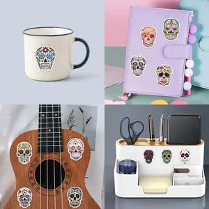 Assorted Day of the Dead skull stickers shown on a mug, notebook, and a ukulele.