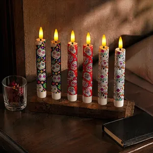 Close-up of six electronic candles featuring colorful sugar skull designs on a rustic wooden base