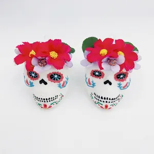 Close-up of Day of the Dead skull decorations with colorful paint and red floral crowns