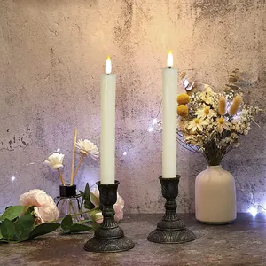Detail of two white LED flameless taper candles on vintage bronze metal holders
